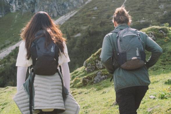 Zomerse opname van twee wandelaars met wandelrugzakken in een sportieve look van achteren