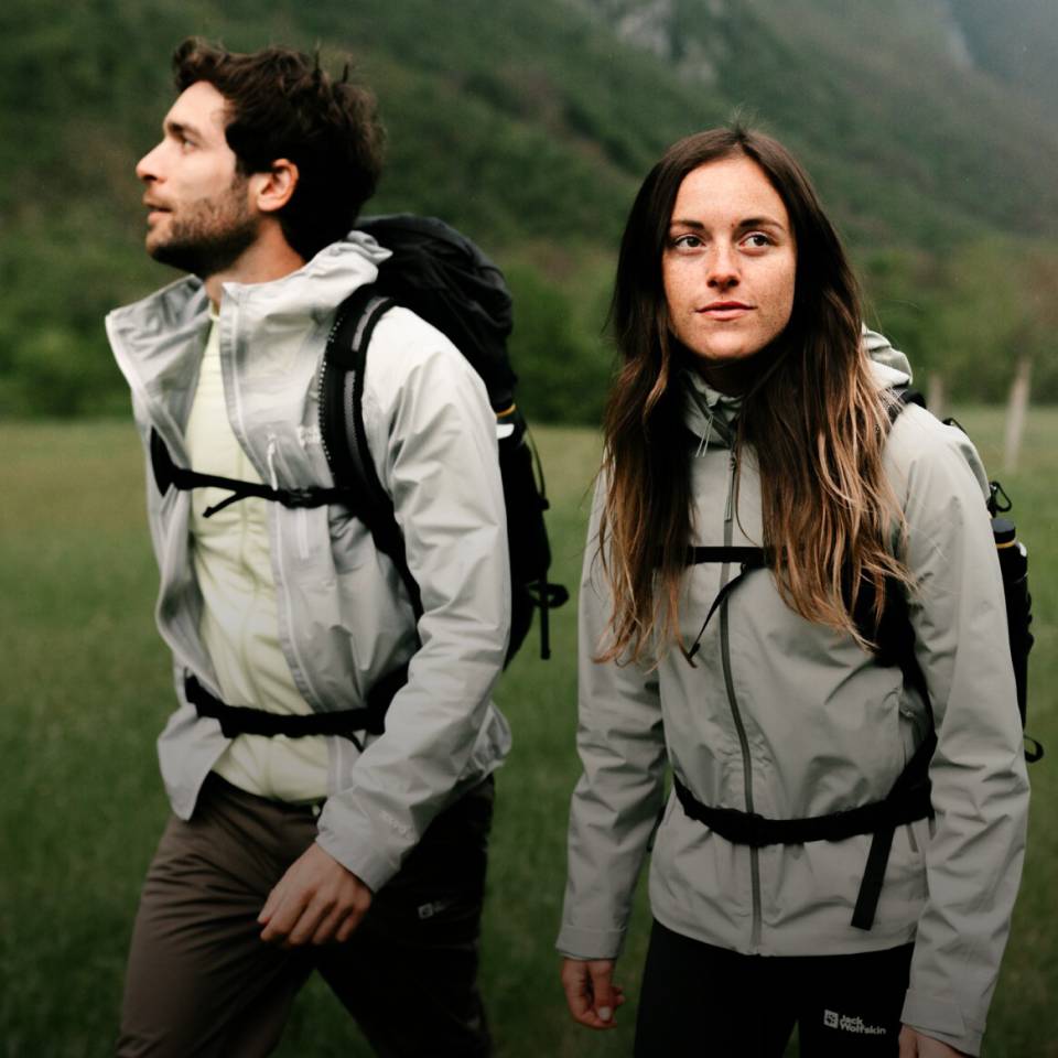 Femme et homme en tenue de randonnée sportive dans un paysage de montagne verdoyant