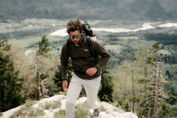 Homme en tenue de randonnée sportive et lunettes de soleil dans un paysage montagneux