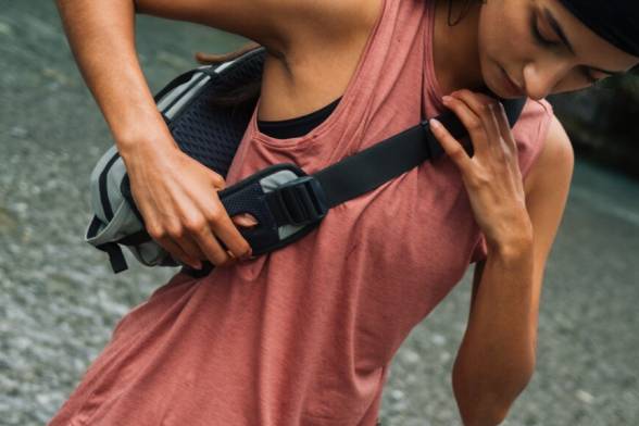 Jonge vrouw in sportieve, zomerse wandelkleding met een sportieve schoudertas