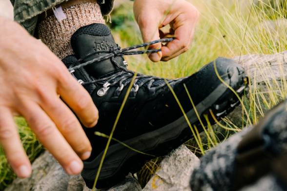 Close-up van een man in zwarte wandelschoenen die zijn schoenen vastmaakt