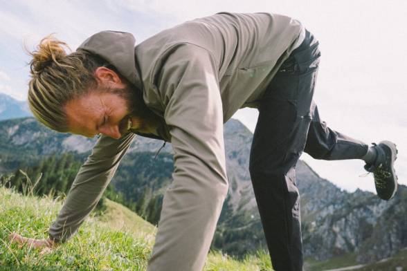 Man in sportieve wandelkleding leunend op een weiland